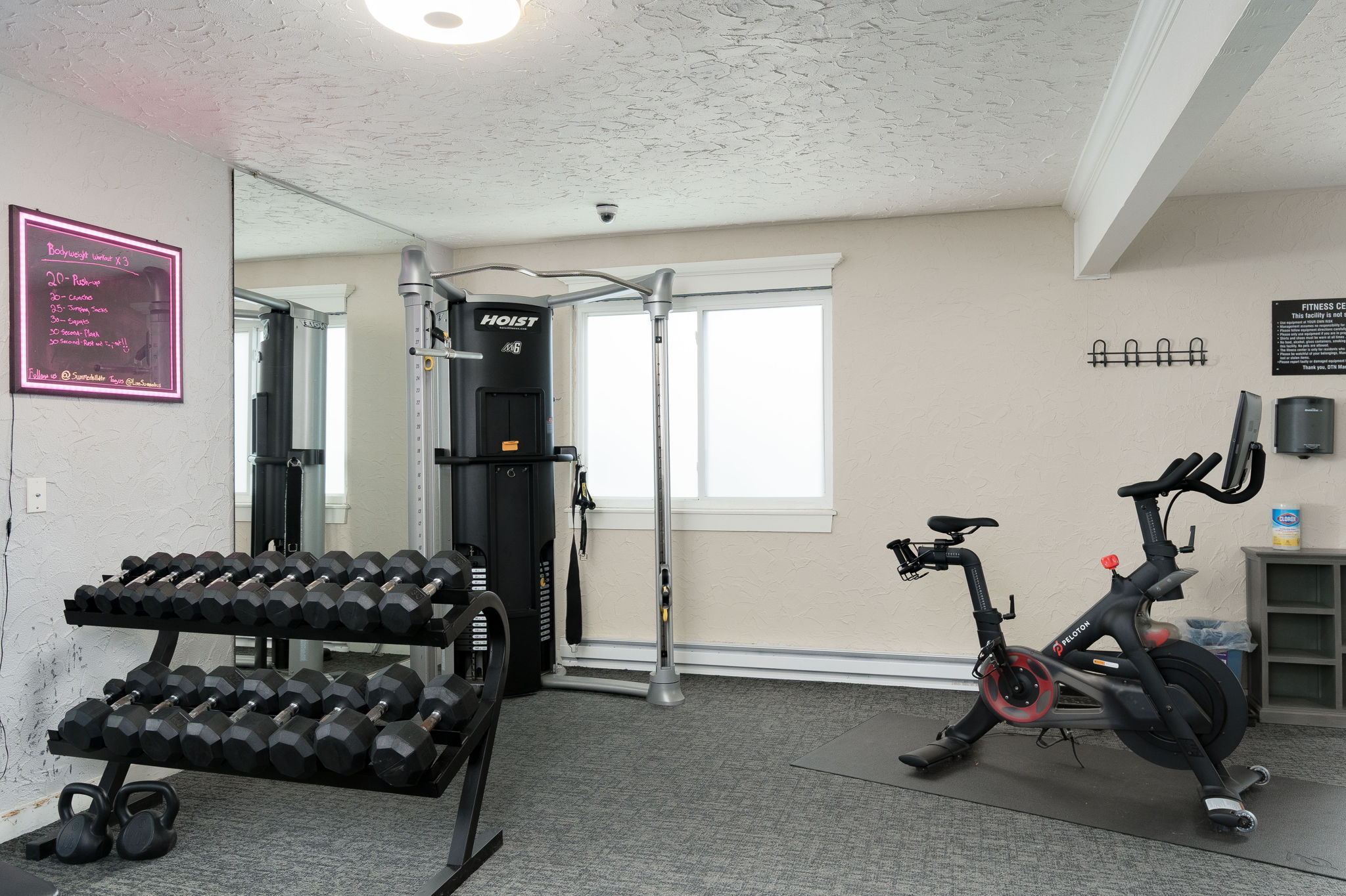 A gym room with a stationary bike, dumbbells, and a mirror.
